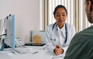 Female doctor consulting a woman patient in a modern medical office for a preventive care checkup.
