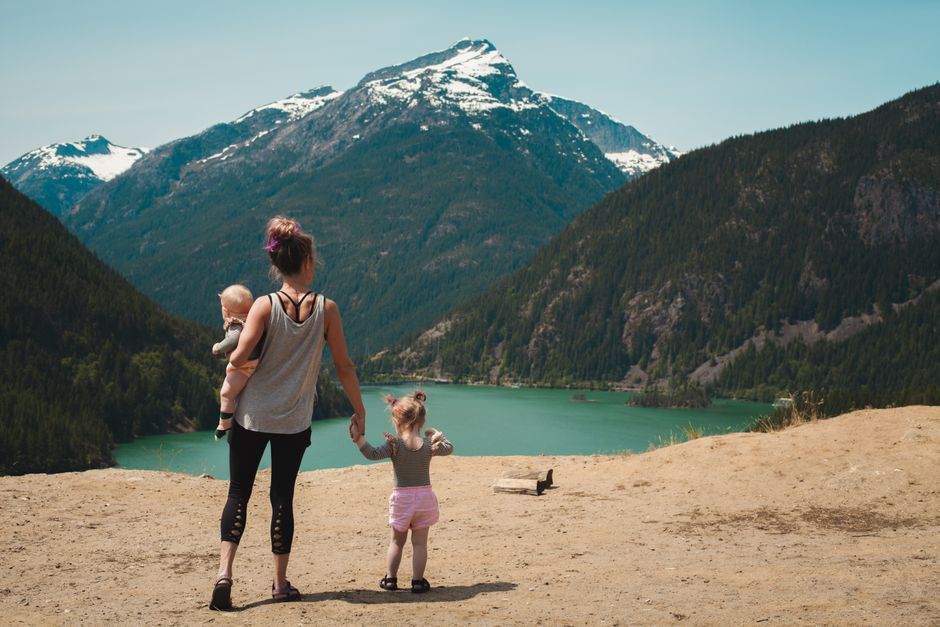 Mother and two young children hiking near a mountain lake in North Idaho on a sunny summer day
