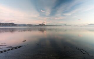 Calm morning light over a lake and forested mountains in North Idaho