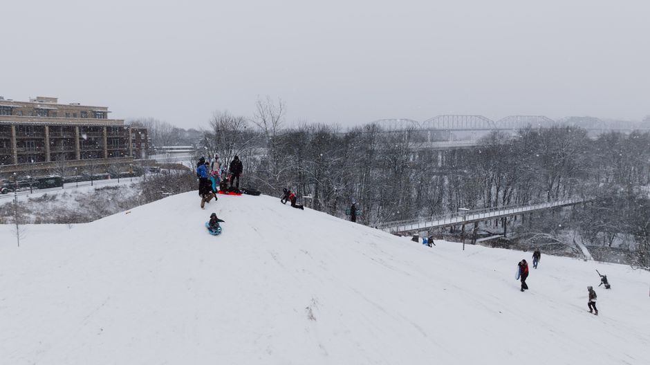 Children sledding down a snowy hill on a bright winter day